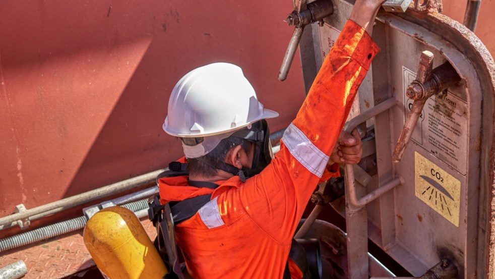 A seaman during fire emergency training drill, on board a merchant cargo ship, wearing fire fighting equipment, breathing apparatus and helmet. Entering the cargo hold protected by CO2 gas system (photo)